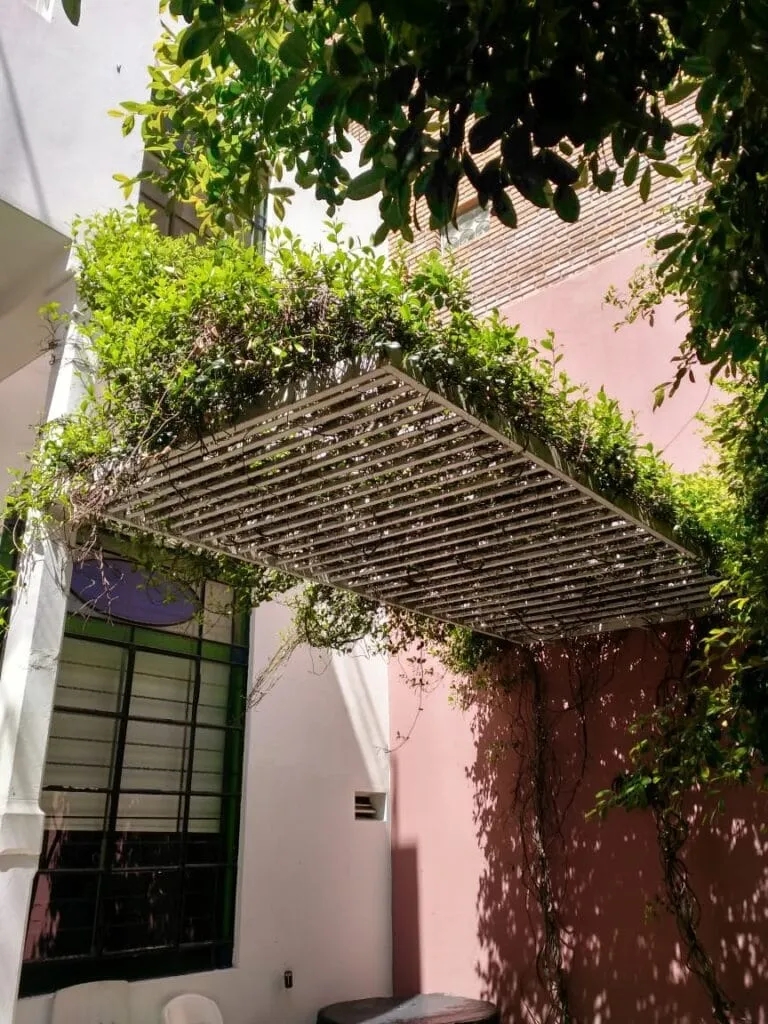 Pérgola de tubos metálicos blancos diseñada por Javier Colomino; estructura suspendida que varía el espaciado para crear un efecto decreciente de sombra