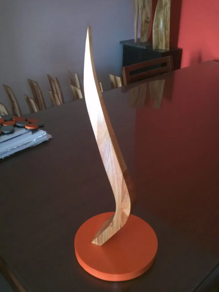 Escultura abstracta de madera multilaminada con base de cuarzo coloreado, creada por el artista escultor arquitecto Javier Colomino